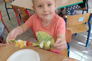 Dzieci robią własnoręcznie szaszłyki owocowe.