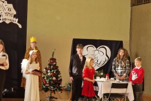 Uczniowie prezentują scenkę przy świątecznym stole.