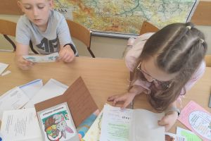 Uczniowie tworzą kolorowe kartki świąteczne z życzeniami.
