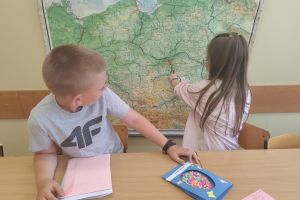 Uczniowie szukają na mapie szkół do których wyślą pocztówki.