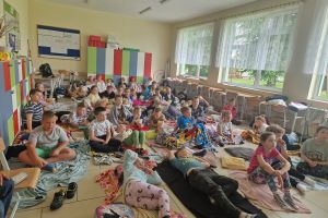 Uczniowie młodszych klas szkoły podstawowej oglądają seans filmowy w sali.