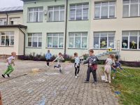 Dzieci puszczają bańki mydlane na placu przed szkołą.