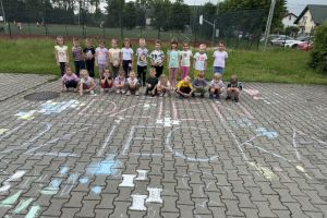 Dzieci malują kredą na chodniku.