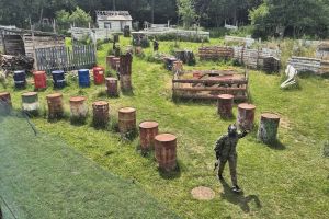 Uczniowie grają w paintball na polu paintballowym.