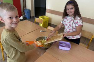 Dzieci dodają owoce do sałatki.