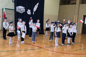 Uczniowie śpiewają z flagami.