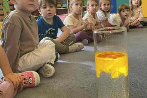 Przedszkolaki obserwują przebieg doświadczenia.