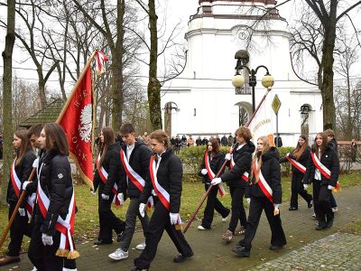 Uczniowie ze sztandarem idą pod Pomnik Niepodległości na skwerku w Borowiu.