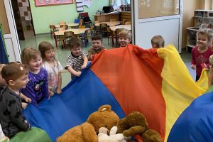 Dzieci uczestniczą w zabawie z misiami z chustą animacyjną