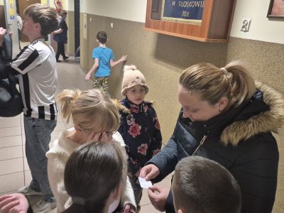 Rodzice i uczniowie losują matematyczne zagadki z tabliczki mnożenia.