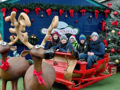 Chłopcy z klasy czwartej siedzą w saniach Mikołaja.
