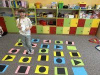 Dzieci gra w grę podłogową o tematyce figur geometrycznych.