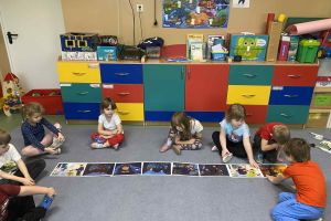 Dzieci uczestniczą w zajęciach na dywanie.