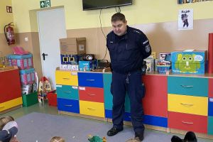 Dzieci słuchają pogadanki policjanta na temat bezpiecznych ferii.