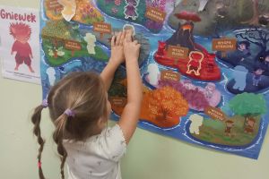 Dzieci przyczepiają odznaki na mapie.