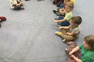 Przedszkolaki tworzą siec z włóczki.