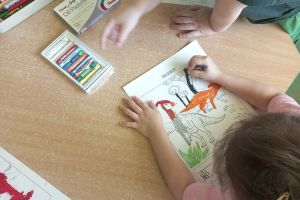 Przedszkolaki kolorują dinozaury.
