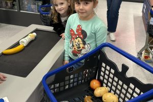 Dzieci skanują produkty na kasie.