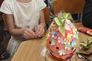 Dzieci ozdabiają styropianową pisankę.