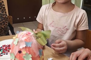 Przedszkolaki naklejają ozdoby na pisankę.