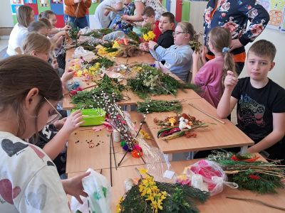 Uczniowie wraz z rodzicami tworzą palmy wielkanocne.