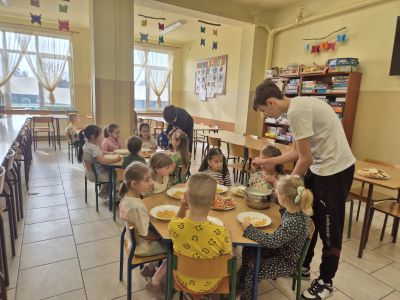 Uczniowie klasy ósmej pomagają zerówkowiczom podczas śniadania.