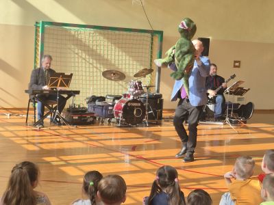 Prowadzący prezentuje maskotkę – smoka.