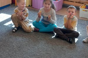 Dzieci uczestniczą w zajęciach na dywanie.